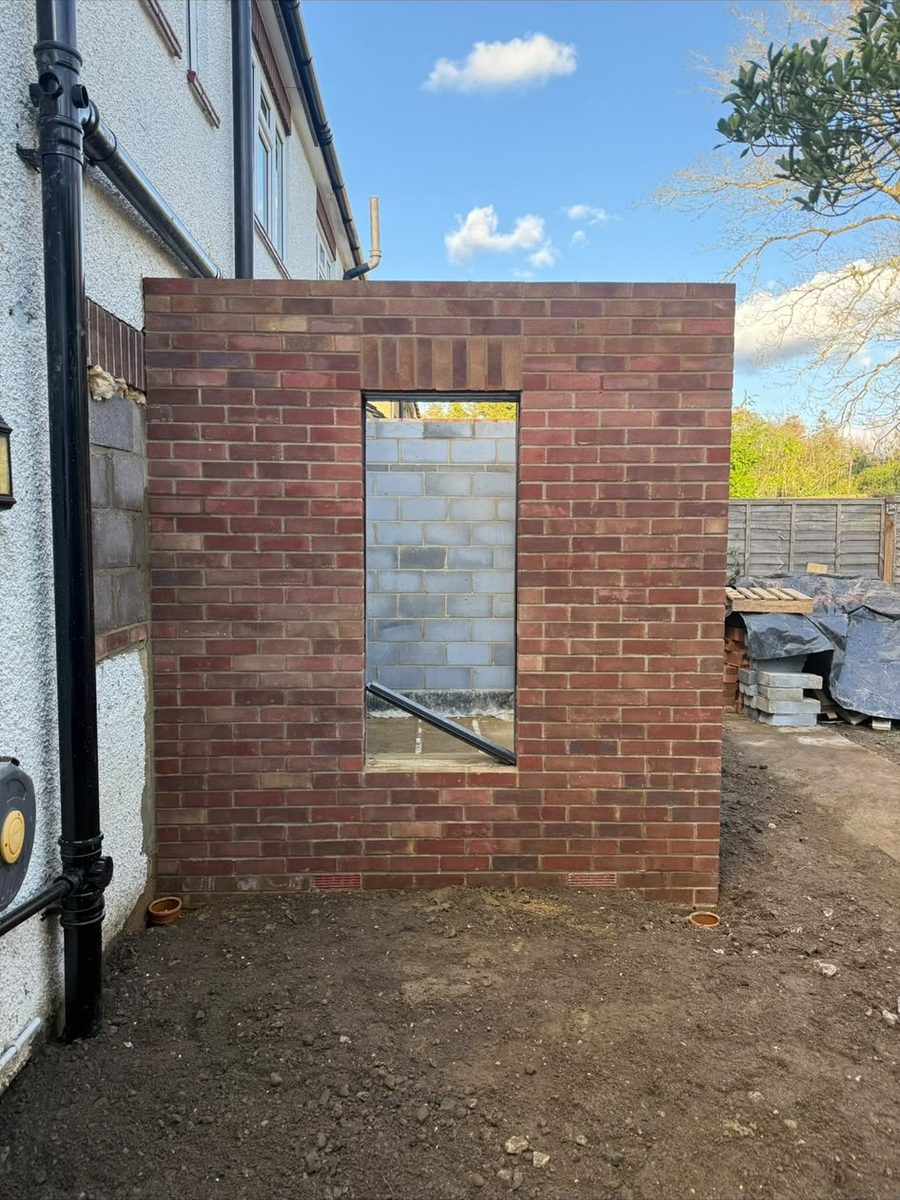 New single-storey extension being built in matching brick with the window opening formed