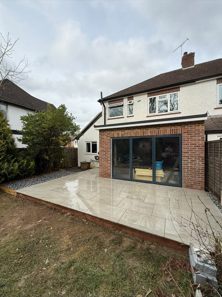 Completed single-storey rear extension in brick with grey bi-fold doors and a porcelain-tiled patio