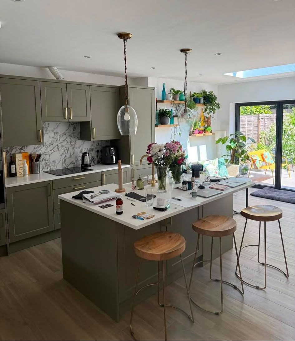 Completed open-plan kitchen extension with a sage-green shaker kitchen, marble splashback, island and bi-fold doors onto the garden