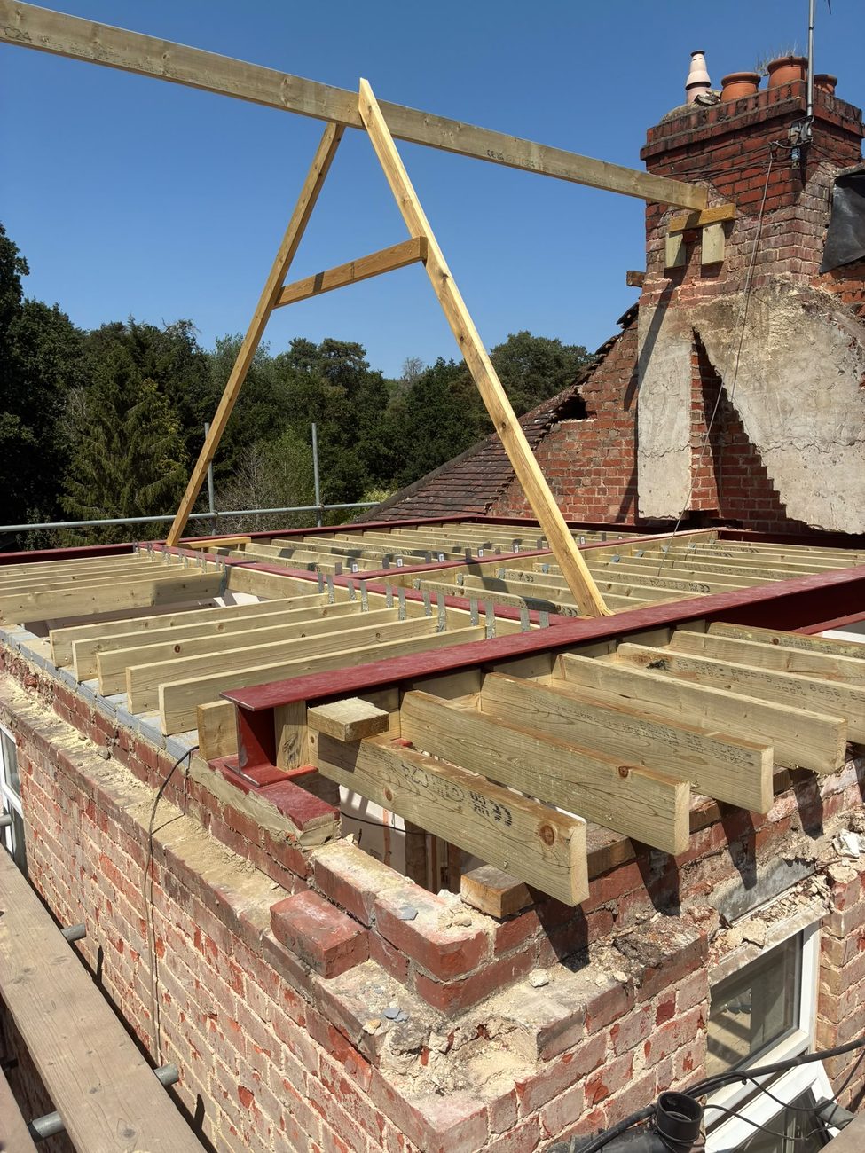 A new timber floor structure on structural steel at roof level during a loft conversion, the roof stripped back to the brick gable