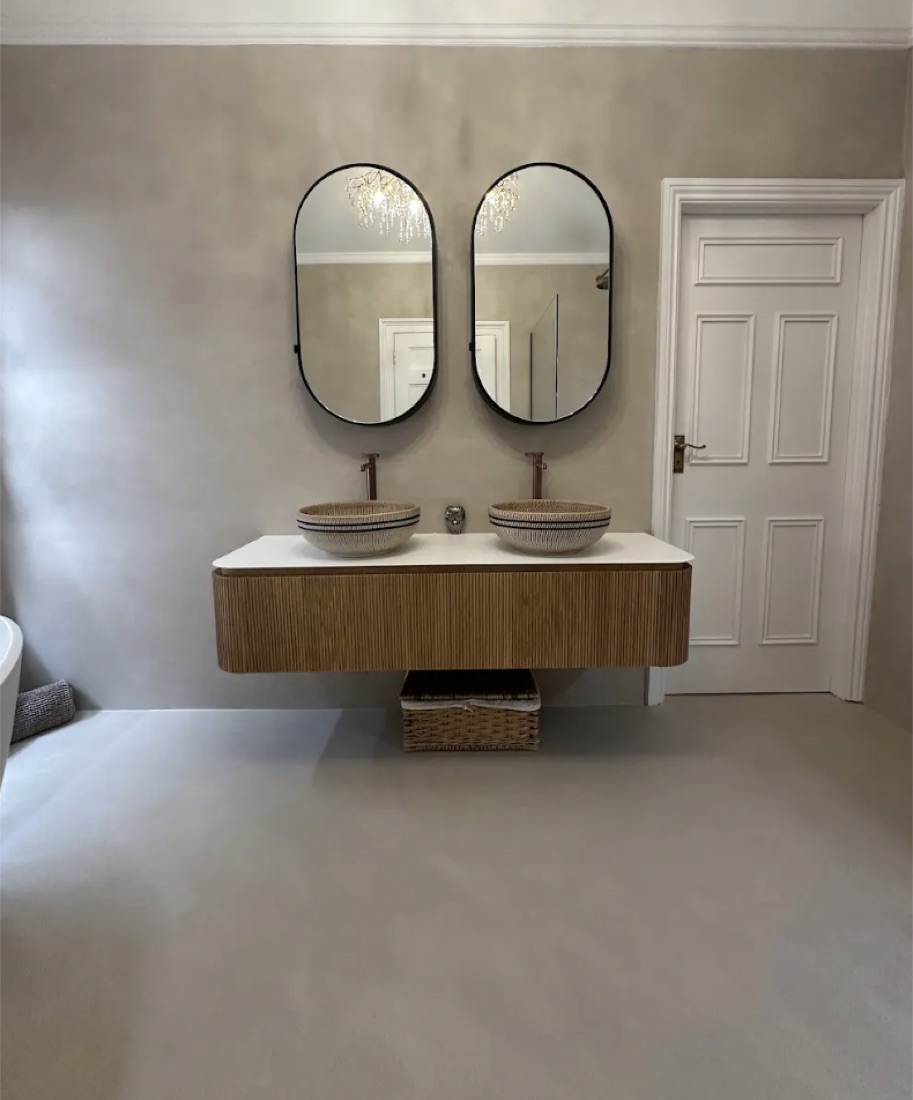 Microcement bathroom with twin oval mirrors, a fluted oak floating vanity and woven vessel basins