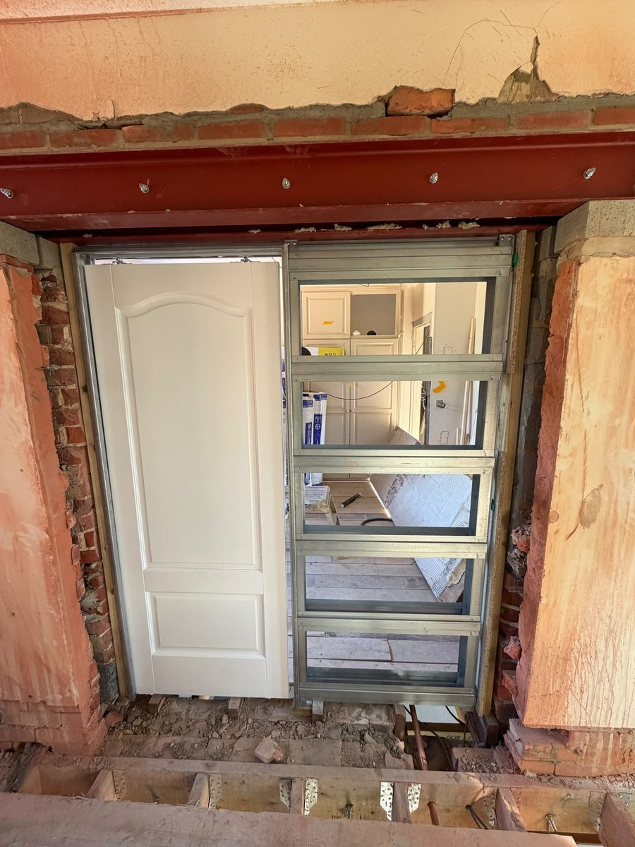 A new doorway formed beneath a steel beam with metal stud framing during a renovation