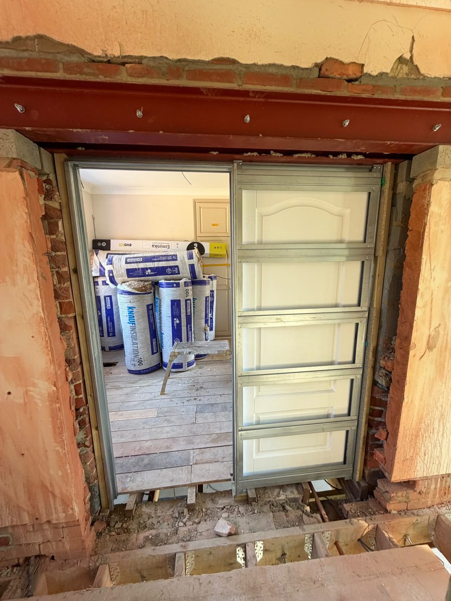 A steel beam over a new opening with acoustic insulation rolls ready for a stud wall