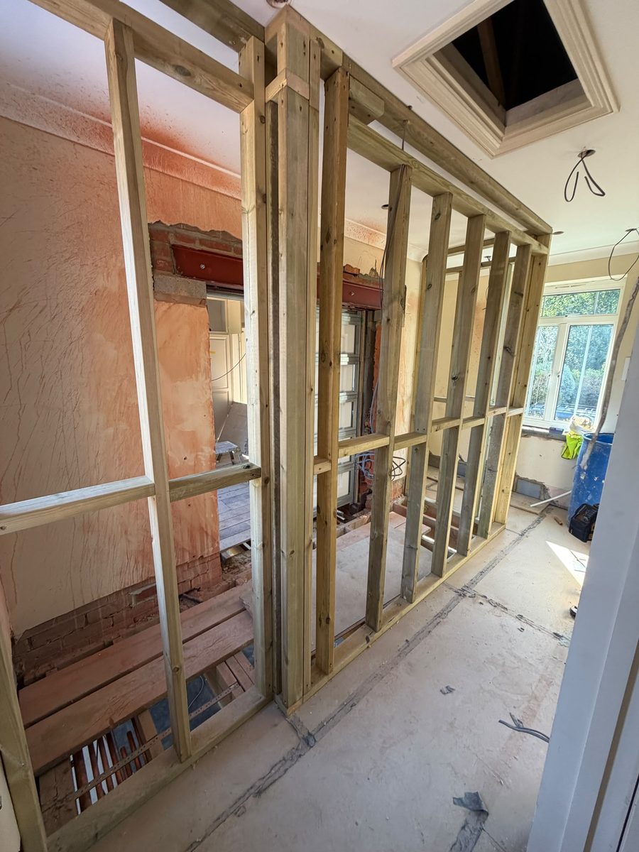 Timber stud partitions and a painted steel beam during a full interior strip-out and reconfiguration