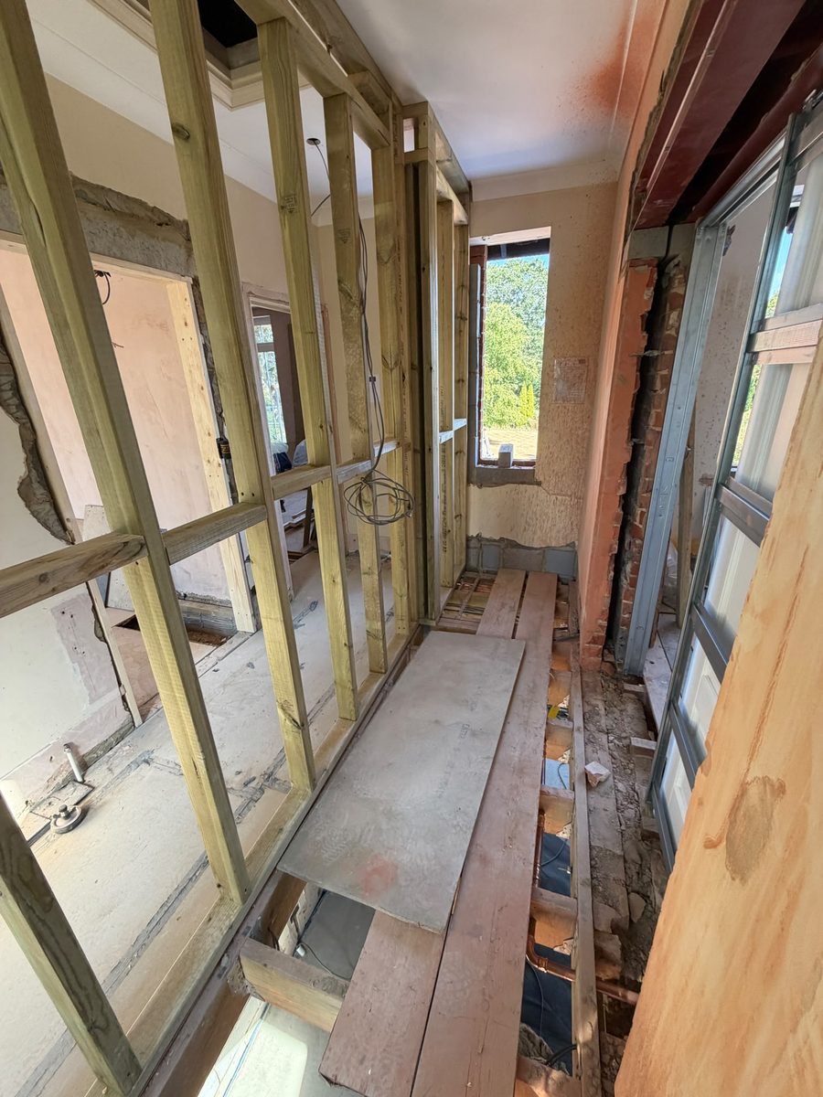 Timber stud partition walls framing a new hallway layout with floorboards lifted for services