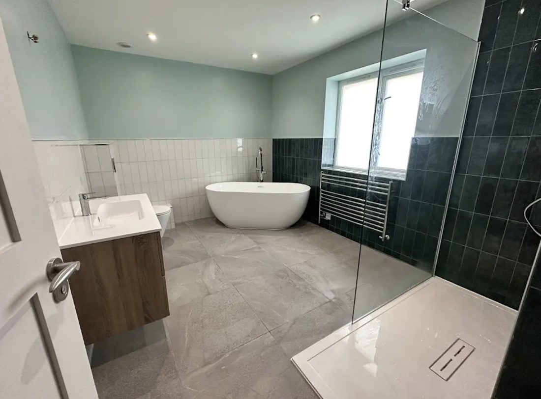 Bathroom in soft teal with a white metro dado, a freestanding bath and a walk-in glass shower